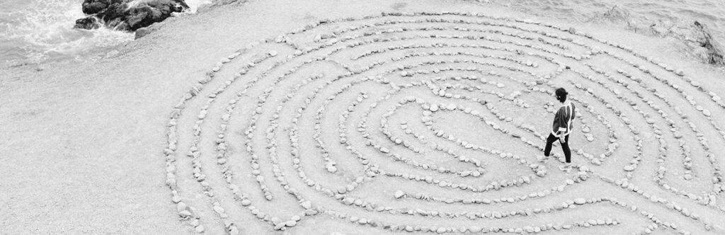 Woman contemplatively navigating a labyrinth, depicted in black and white.